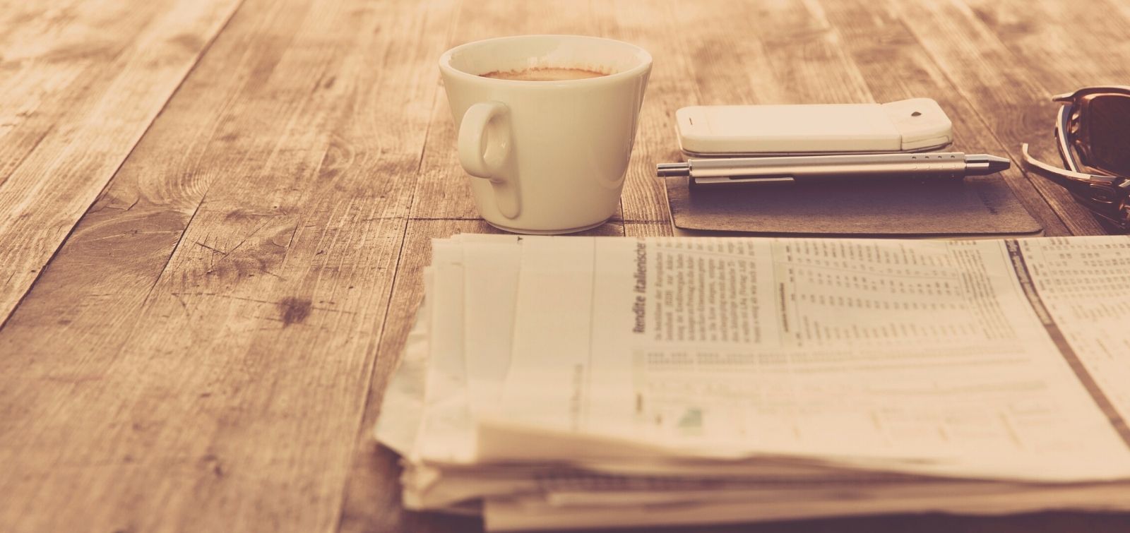 newspaper, coffee, and phone on tabletop